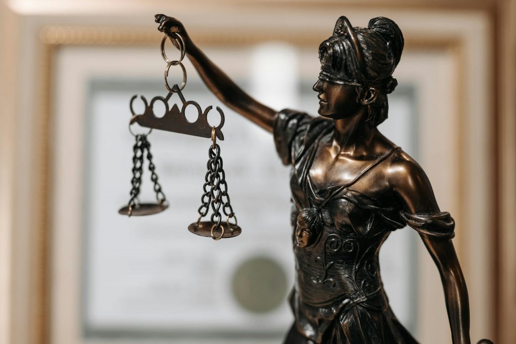 Close-up of a bronze Lady Justice statue holding scales in an office environment.